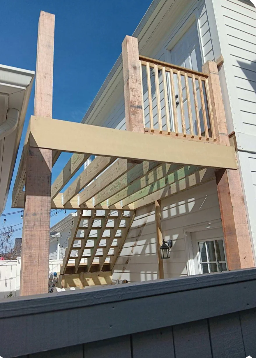 Cedar wood pergola with lattice panels and upper deck railing attached to residential home