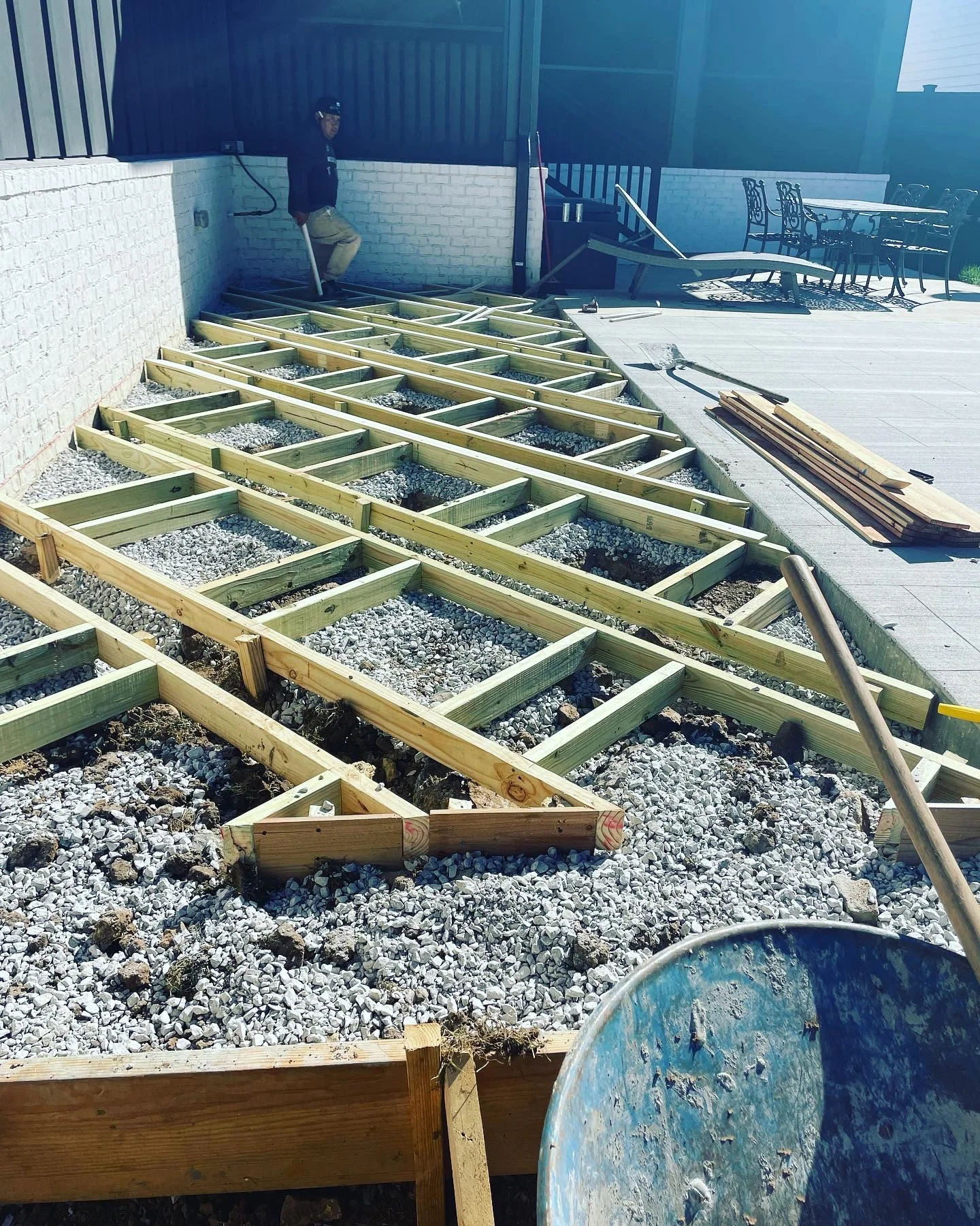 Pressure-treated wood deck framing with gravel base and joist installation in progress