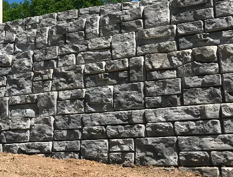Gray granite stone retaining wall with stacked rectangular blocks in running bond pattern