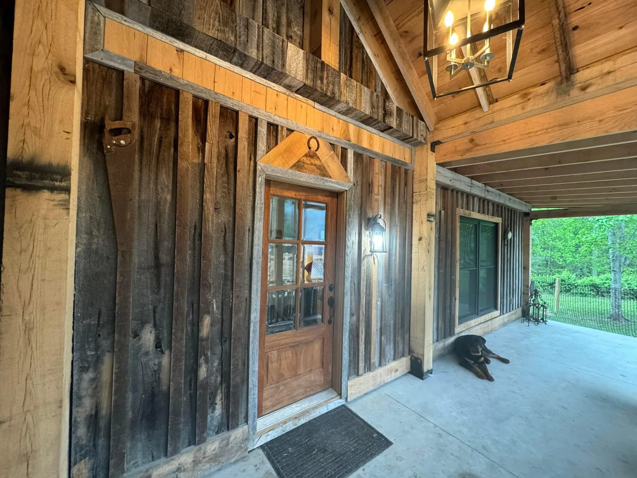 Covered patio with weathered wood siding, wooden door, and exposed beam ceiling