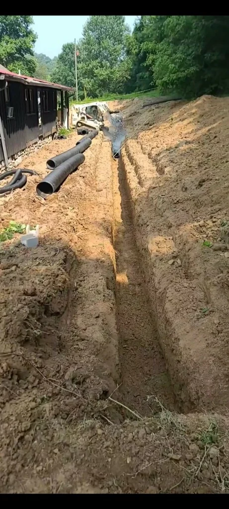 Drainage trench with corrugated pipe installation and excavation equipment on residential property