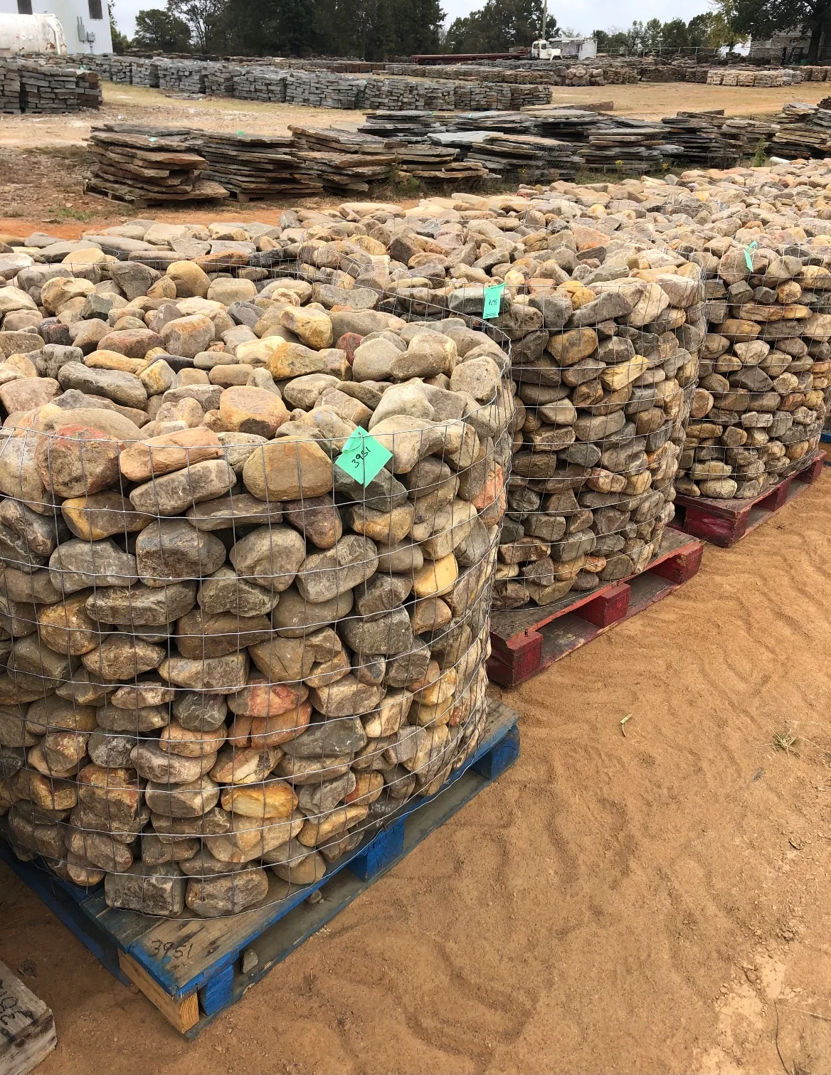 Gabion baskets filled with natural stone boulders and stacked flagstone materials at job site