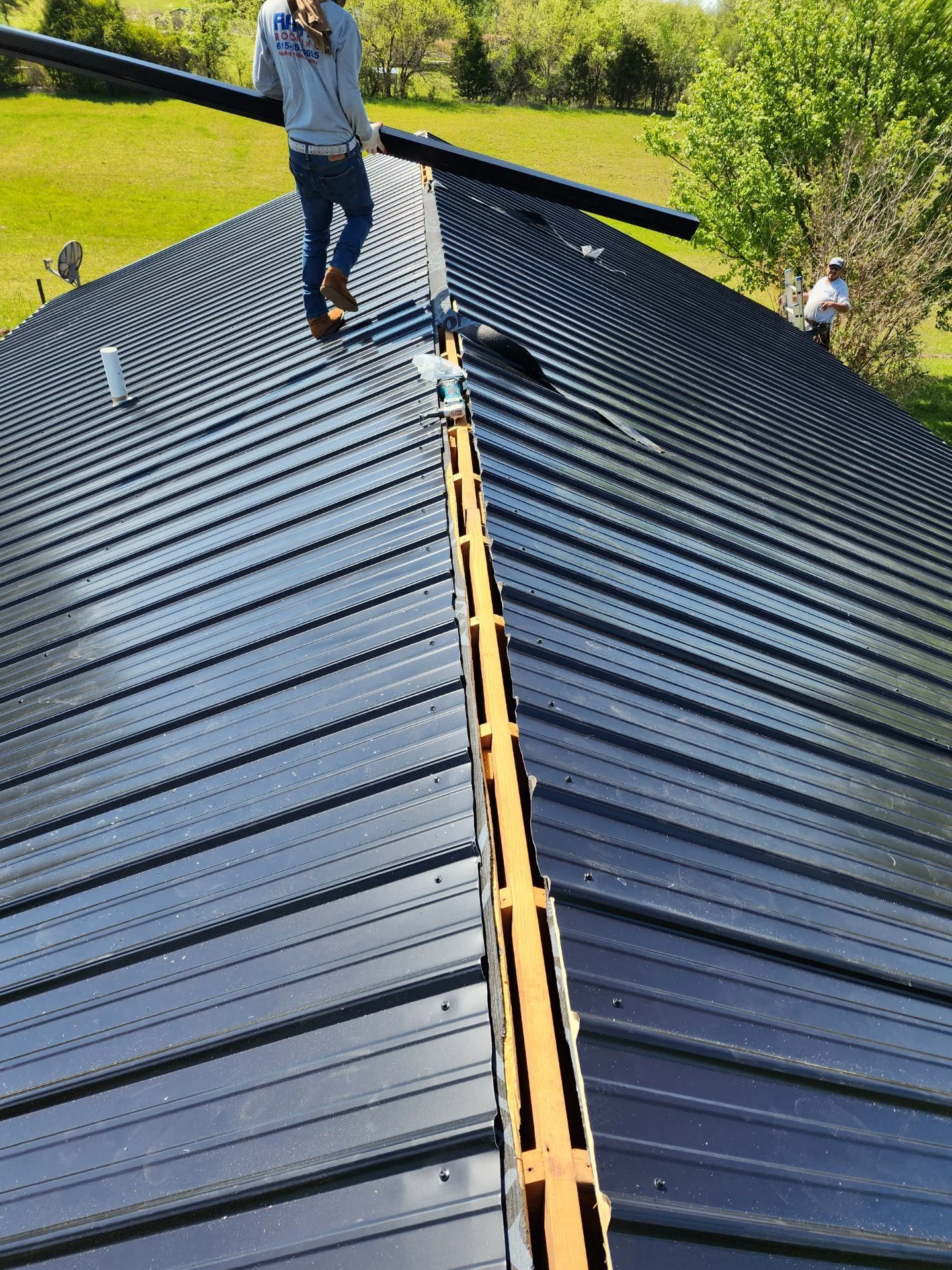 Metal roof installation with standing seam panels and yellow safety ladder on residential structure