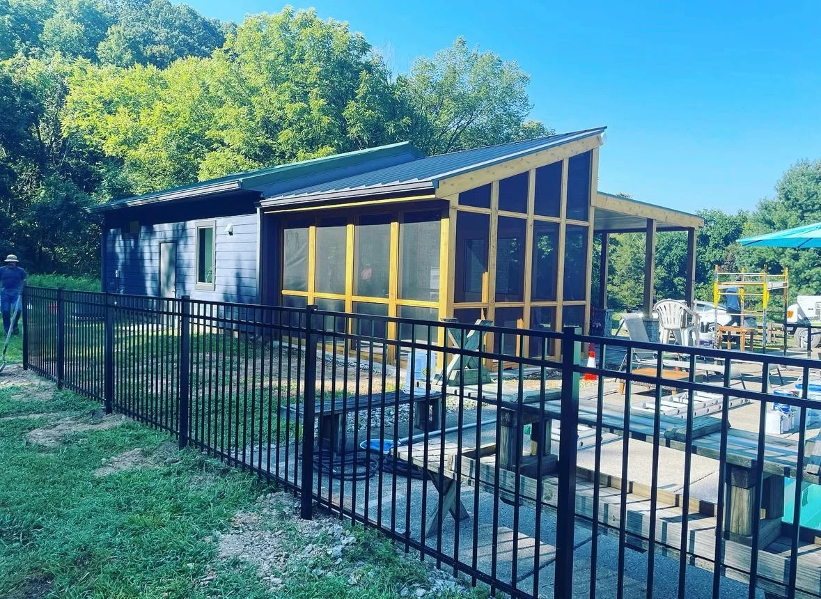 Modern backyard structure with metal roof, black-framed windows, and covered patio deck